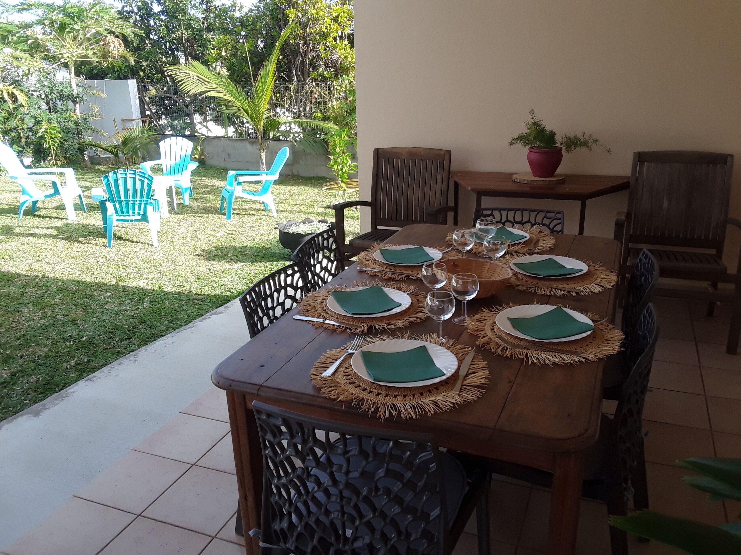 A wooden dining table set for six with woven placemats and green napkins, surrounded by chairs.