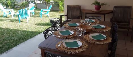 A wooden dining table set for six with woven placemats and green napkins, surrounded by chairs.