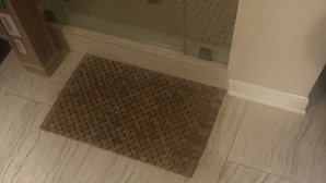 A tiled floor with a patterned mat in the center.