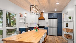 Una cucina moderna con tavolo da pranzo in legno, mobili bianchi ed elettrodomestici in acciaio inossidabile.