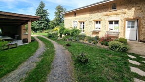 Un bâtiment en pierre doté d’un patio couvert et d’un chemin de gravier menant à celui-ci.