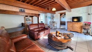 Un salon au style rustique, avec un canapé en cuir, une table basse en bois et un téléviseur.