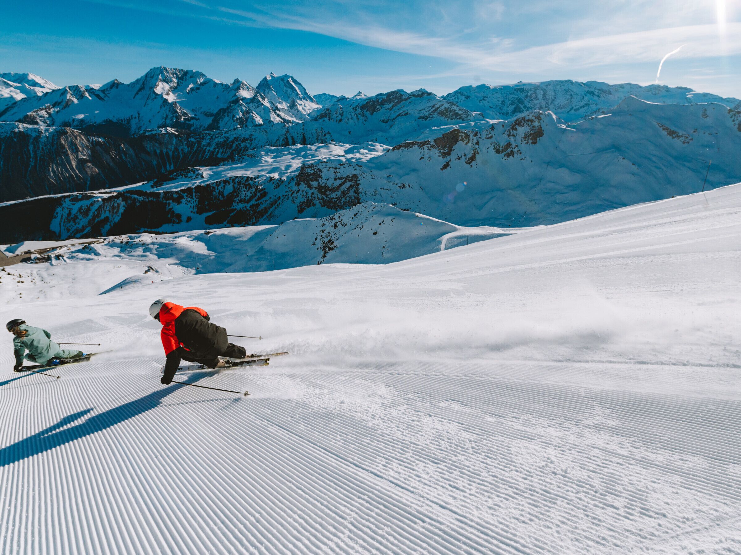 A snowy ski slope with skiers and a mountainous backdrop.