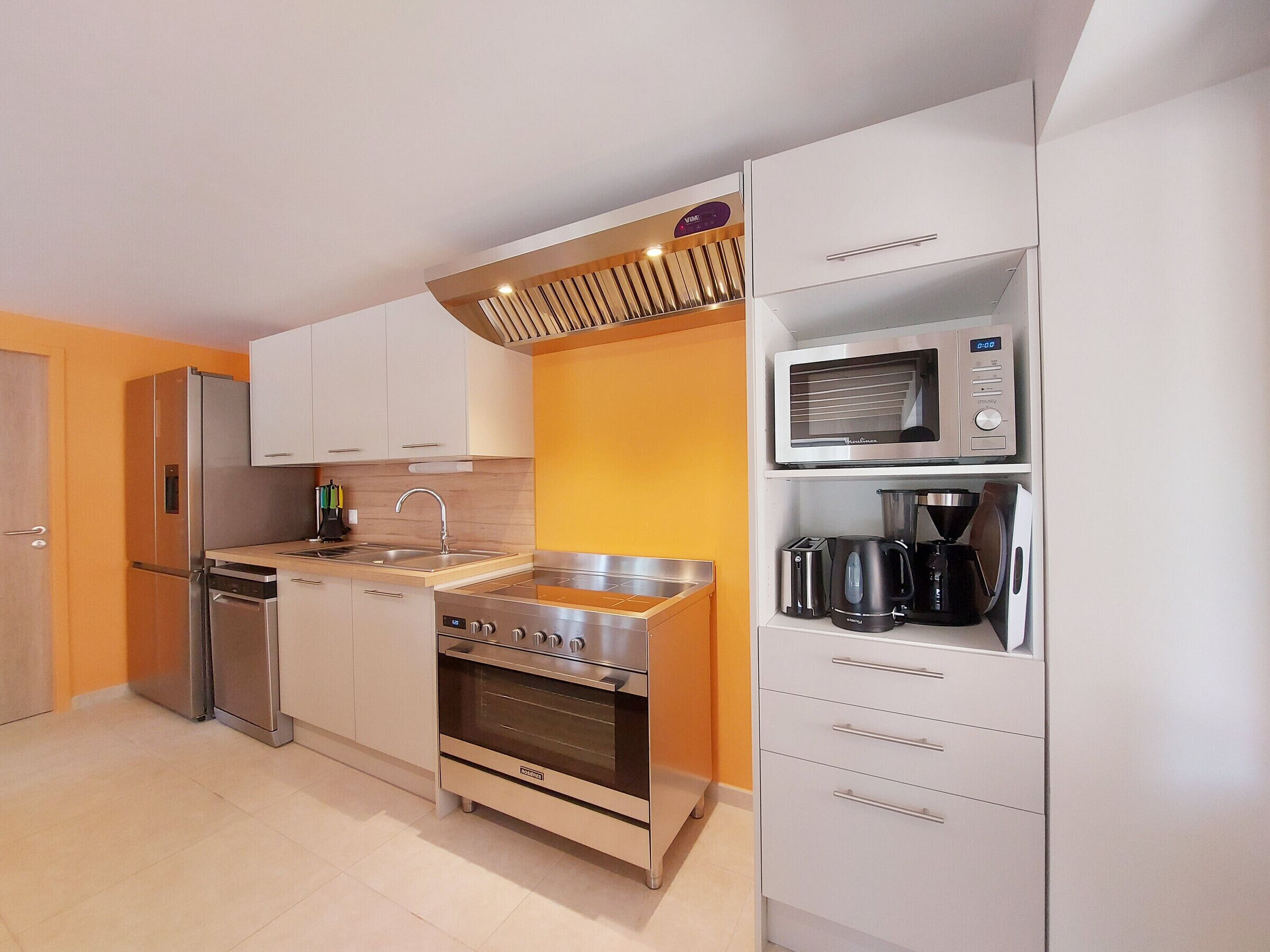 A compact kitchen with a built-in oven, microwave, and a coffee maker on the countertop.