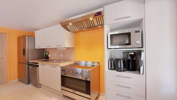 A compact kitchen with a built-in oven, microwave, and a coffee maker on the countertop.