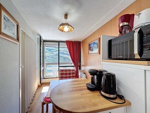 Uma cozinha compacta com uma mesa de madeira, uma cafeteira e um micro-ondas Samsung.