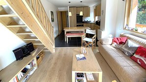 Un intérieur moderne comprenant un escalier, un coin repas, une cuisine et un salon avec un canapé et une fenêtre.