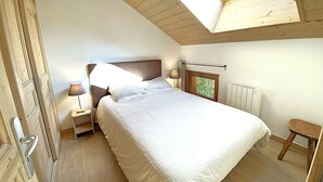 Une chambre à coucher avec un puits de lumière, un lit, une table de chevet, une lampe et un radiateur.