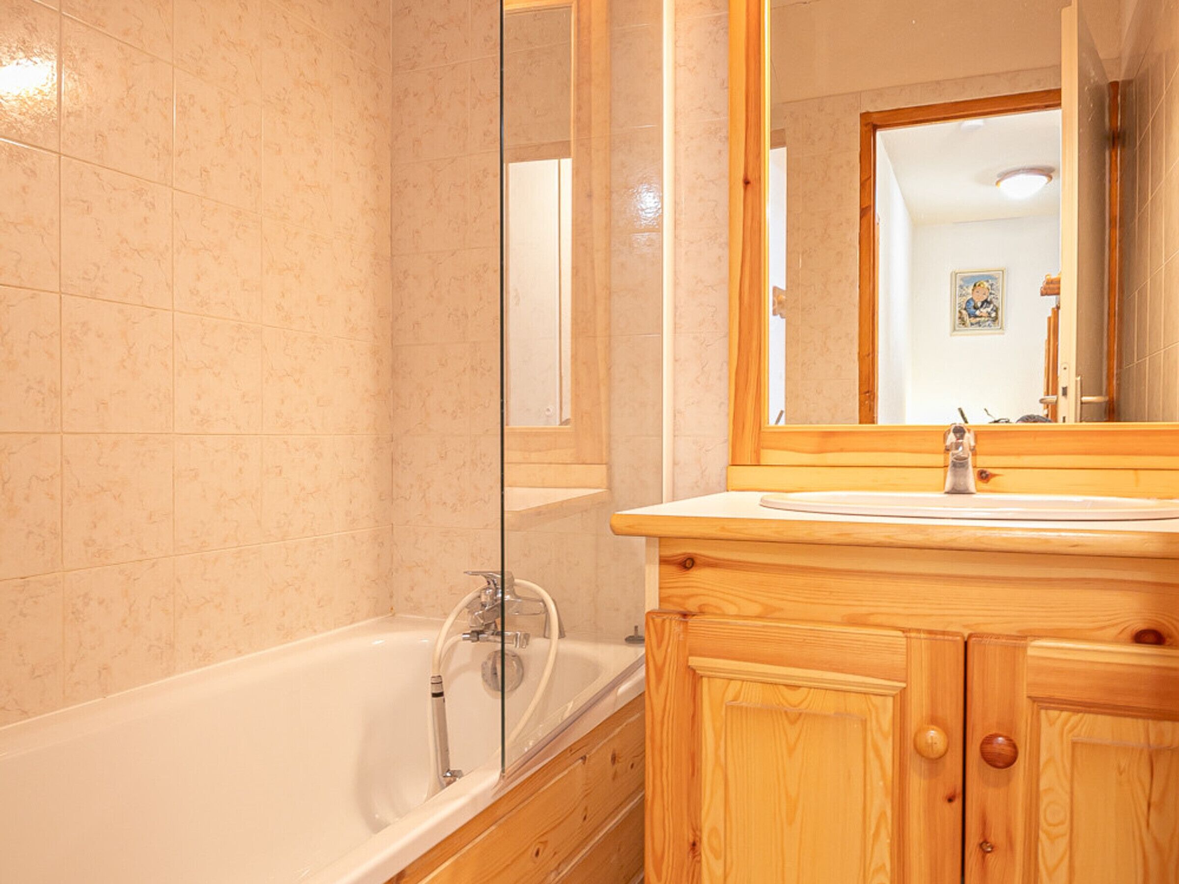 Une salle de bain avec une baignoire, un meuble-lavabo en bois et un grand miroir.