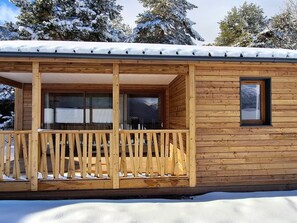 Une cabane en bois dotĂ©e dâun balcon, de grandes fenĂȘtres et dâune porte.