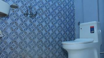 Une salle de bain avec un mur recouvert de carreaux à motifs, des toilettes et un robinet.