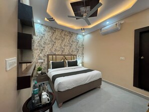 Une chambre d’hôtel moderne équipée d’un lit, d’une table de chevet et d’un ventilateur de plafond.