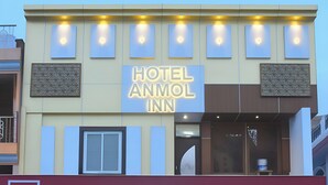 A hotel with a sign reading "HOTEL ANMOL INN" and a bank named "IDFC FIRST Bank" below it. - Hotel Anmol Inn (Karchana)