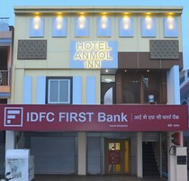 A hotel with a sign for Hotel Anmol Inn and a bank named IDFC First Bank.