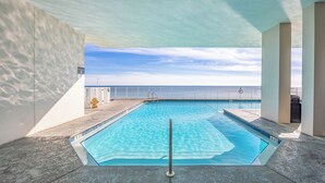 A swimming pool with clear blue water, surrounded by a white wall and a railing, with a view of the ocean in the background. - New Listing! Forever View From The 7th Floor At Popular Windemere Resort! (Pensacola)