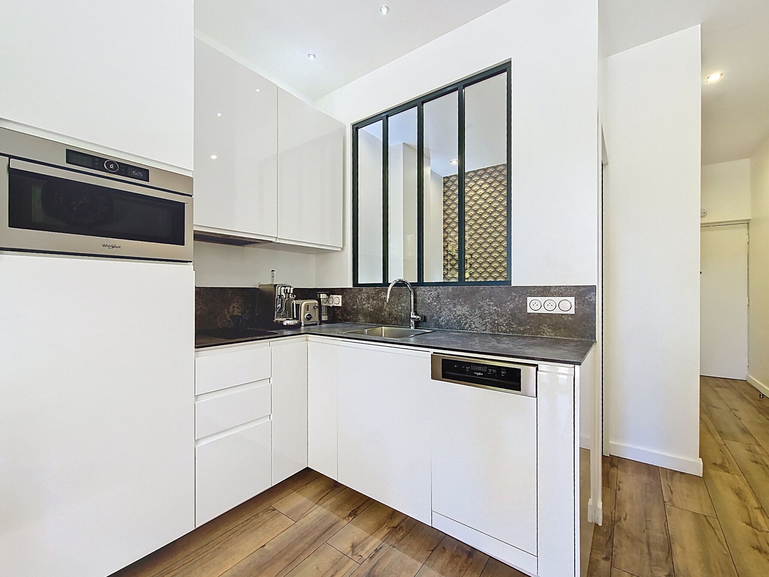 A compact kitchen with white cabinetry, a built-in microwave, a toaster, and a dishwasher.