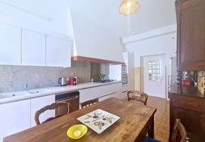 A compact kitchen with a dining table, chairs, and a coffee maker. - N&J - BLEU PANORAMA - Sea View (Niza)