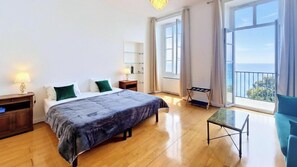 Ein Schlafzimmer mit einem Bett, Nachttischen, einem kleinen Tisch und einem Fenster mit Blick.