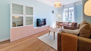 Ein modernes Wohnzimmer mit Fernseher, eine Vitrine, einer Couch und einem Essbereich.