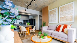 Een moderne woonkamer met een bank, salontafel en decoratieve planten.