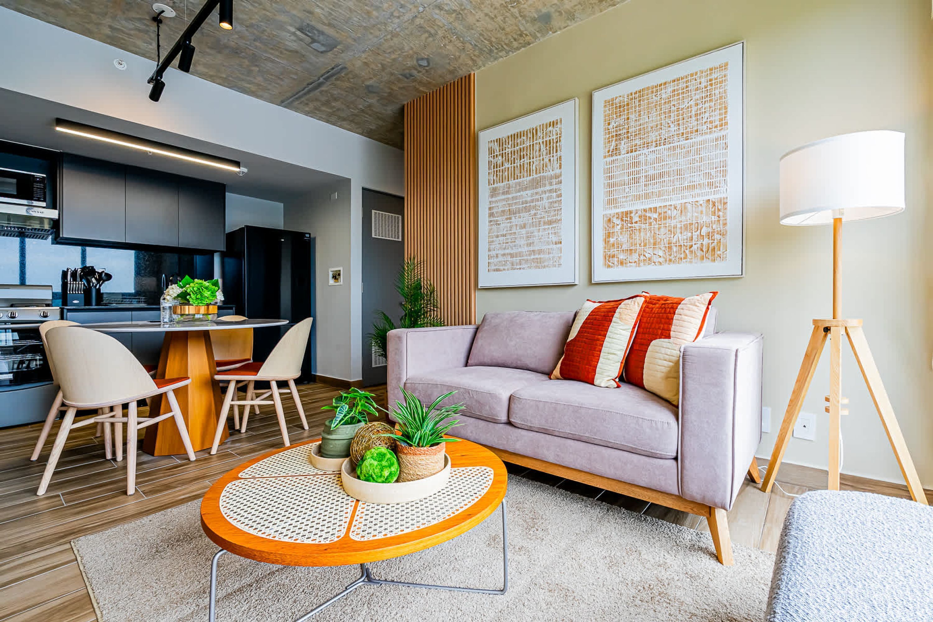 A modern living room with a sofa, a round coffee table, and a dining area with chairs and a table.