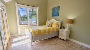 A bedroom with a bed, a nightstand, a lamp, a window, and a painting on the wall. - Oversized Family Resort Home w/Golf Cart (Michigan City)