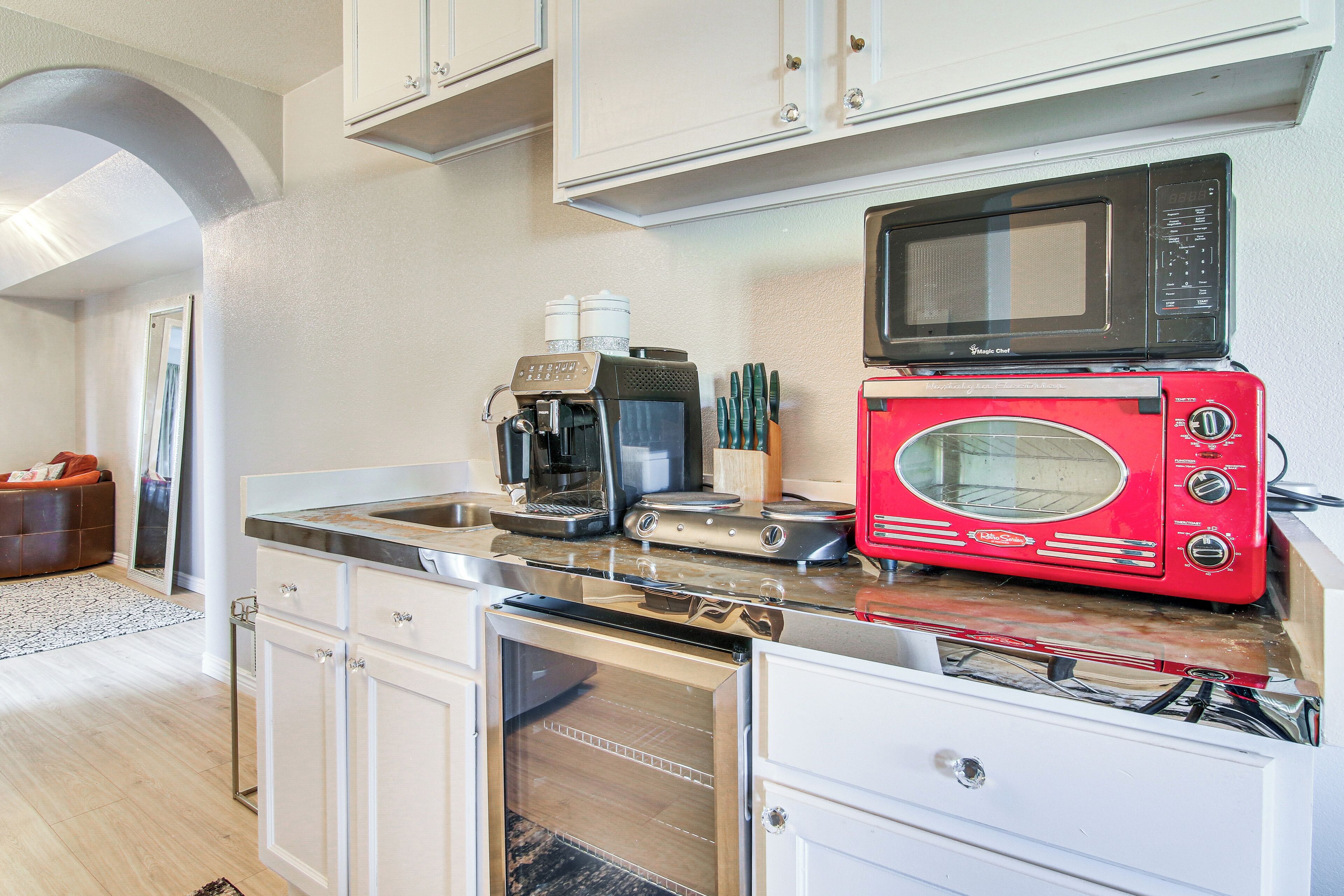 Una cocina moderna con electrodomésticos de acero inoxidable, microondas, tostadora roja y cafetera.