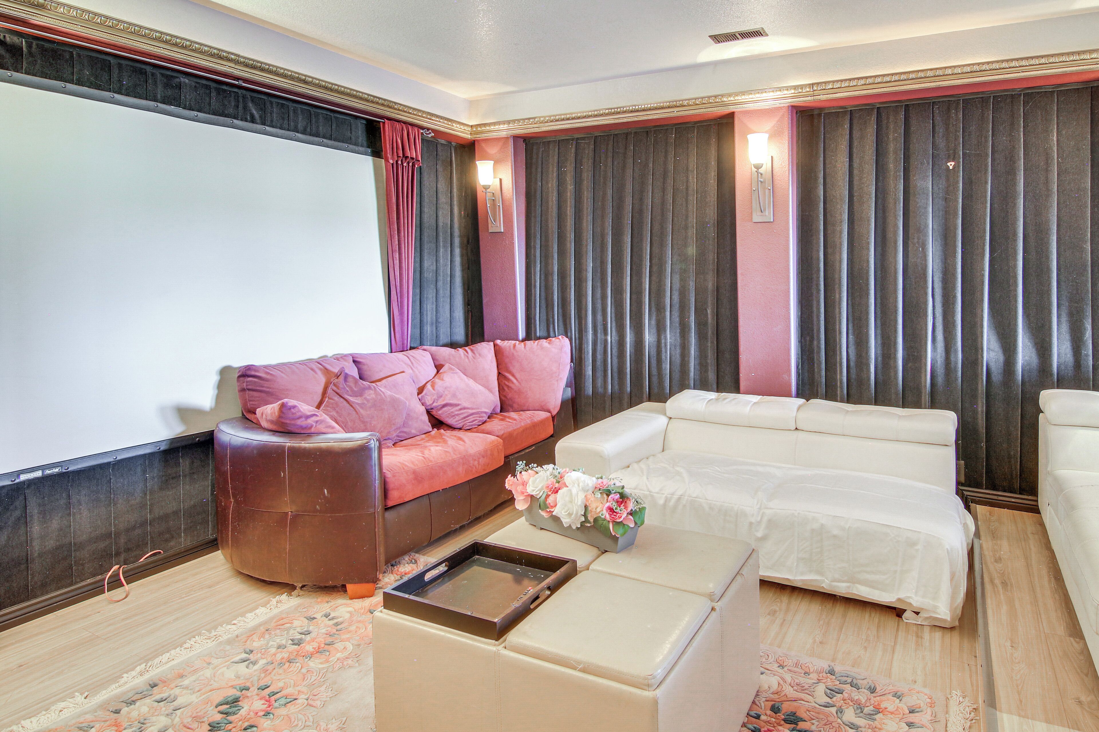 A living room with a large screen, two sofas, a coffee table, and a floral arrangement.