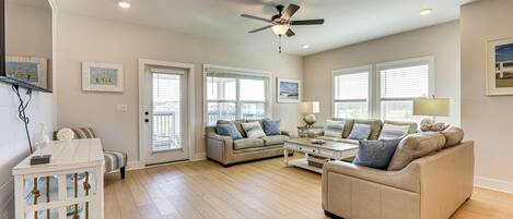 A spacious living room with a beige sofa, a white coffee table, and a ceiling fan.
