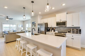 A modern kitchen with white cabinetry, a large island with bar stools, stainless steel appliances, and pendant lighting. - Easy Beach Access: New PCB Retreat w/ Resort Pool! (Panama City Beach)
