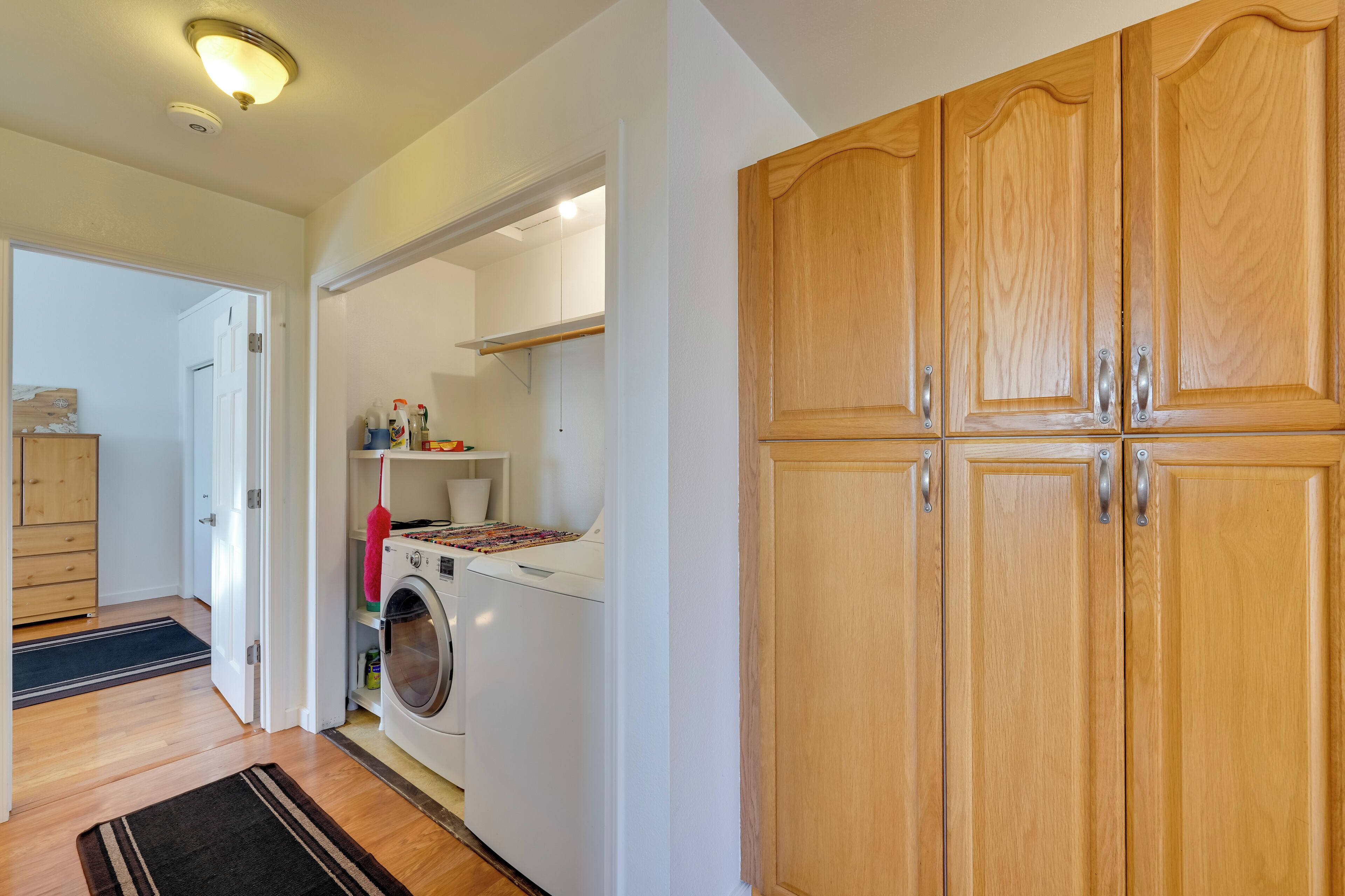 A laundry area with a washing machine and dryer, wooden cabinets, and a white door.