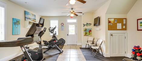 A home gym with exercise equipment, a ceiling fan, and artwork on the walls.
