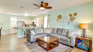 A modern living room with a grey sectional sofa, a wooden coffee table, and a ceiling fan. - Steps to Sea! Cottage w/ Pools in Port St Joe (Port St. Joe)