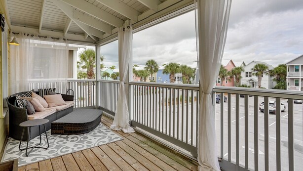 A covered porch with a sofa and table, a patterned rug, and a view of a street with palm trees and houses. - Steps to Sea! Cottage w/ Pools in Port St Joe (Port St. Joe)