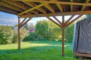 A wooden structure with a roof, surrounded by greenery and a house in the background. - Fish & Hike! Home Base for Kachemak Bay Adventures (Homer)