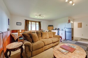 A living room with a sofa, a round coffee table, and a dining area with a table and chairs. - Fish & Hike! Home Base for Kachemak Bay Adventures (Homer)