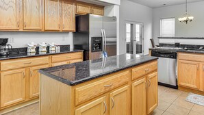 A kitchen with wooden cabinets, stainless steel appliances, and a granite countertop. - Easy ABQ Access: Large Family Home w/ Patio & Yard (Rio Rancho)
