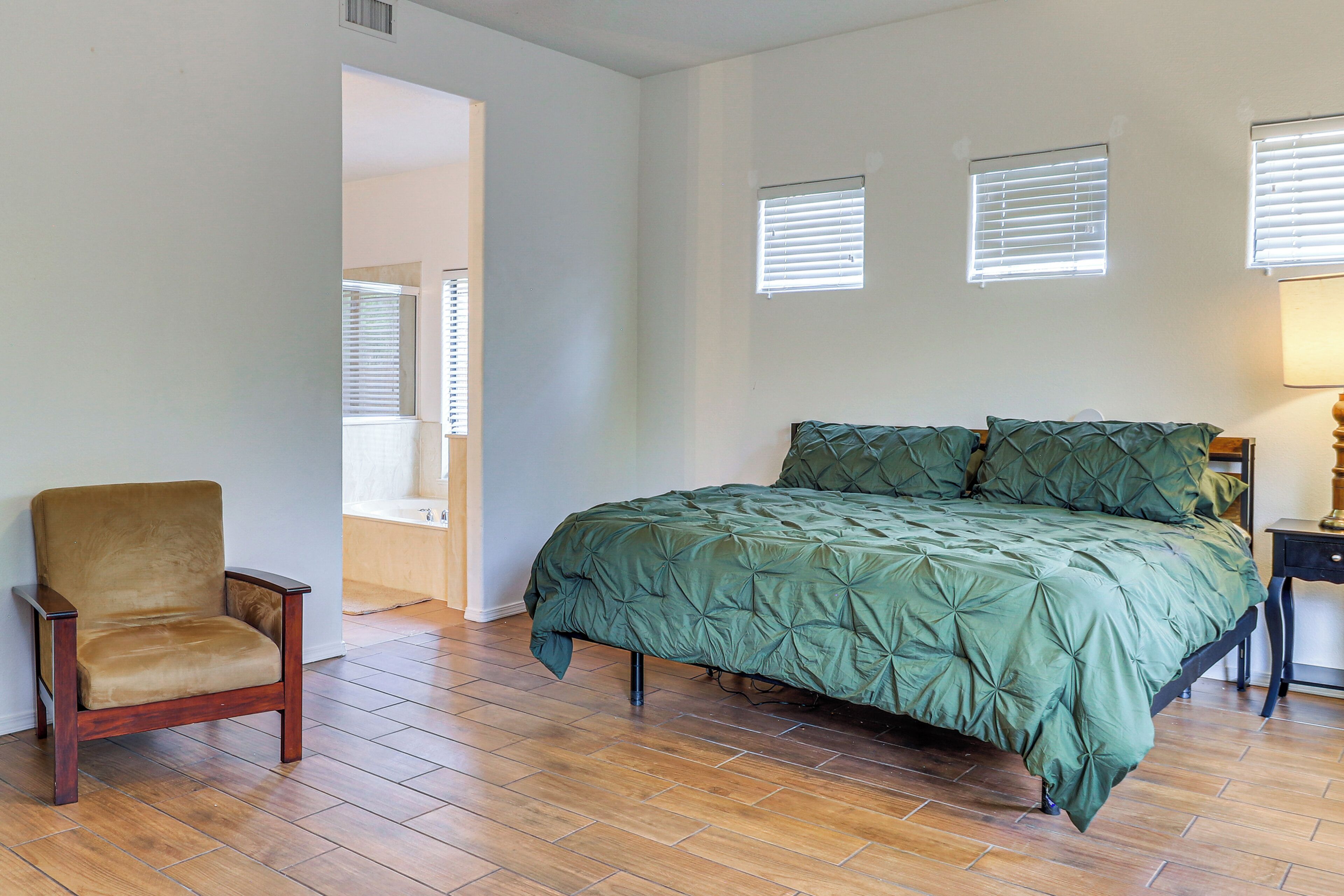 A bedroom with a bed, a chair, and a nightstand.