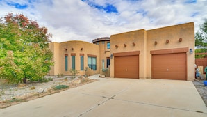 A two-story building with a flat roof, large garage doors, and a paved driveway. - Easy ABQ Access: Large Family Home w/ Patio & Yard (Rio Rancho)