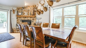 Un coin repas agrémenté d’une cheminée en pierre, de têtes de cerf décoratives et d’une grande fenêtre.