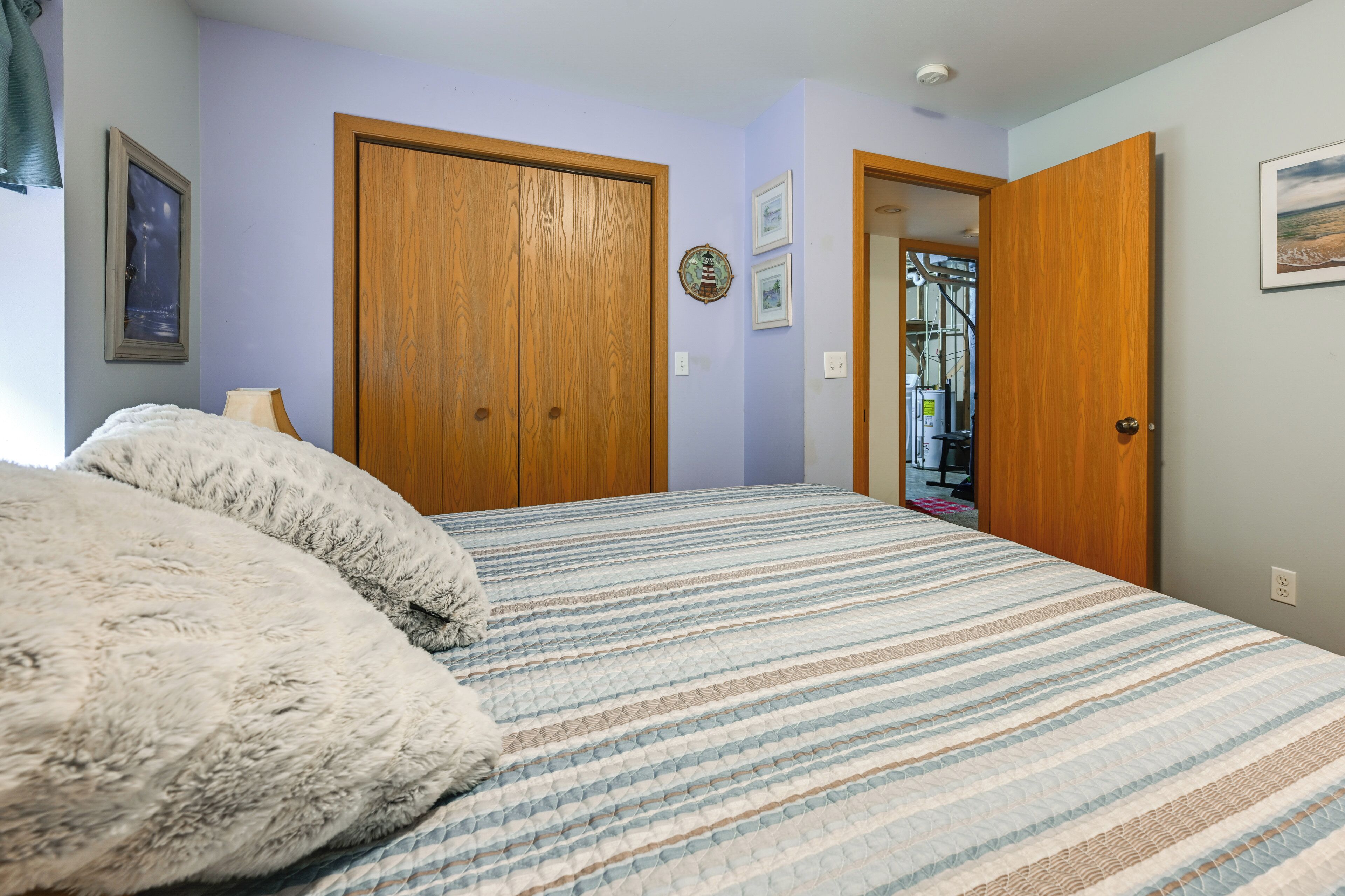 Un dormitorio con una cama grande, dos puertas de madera y vistas a otra habitación.