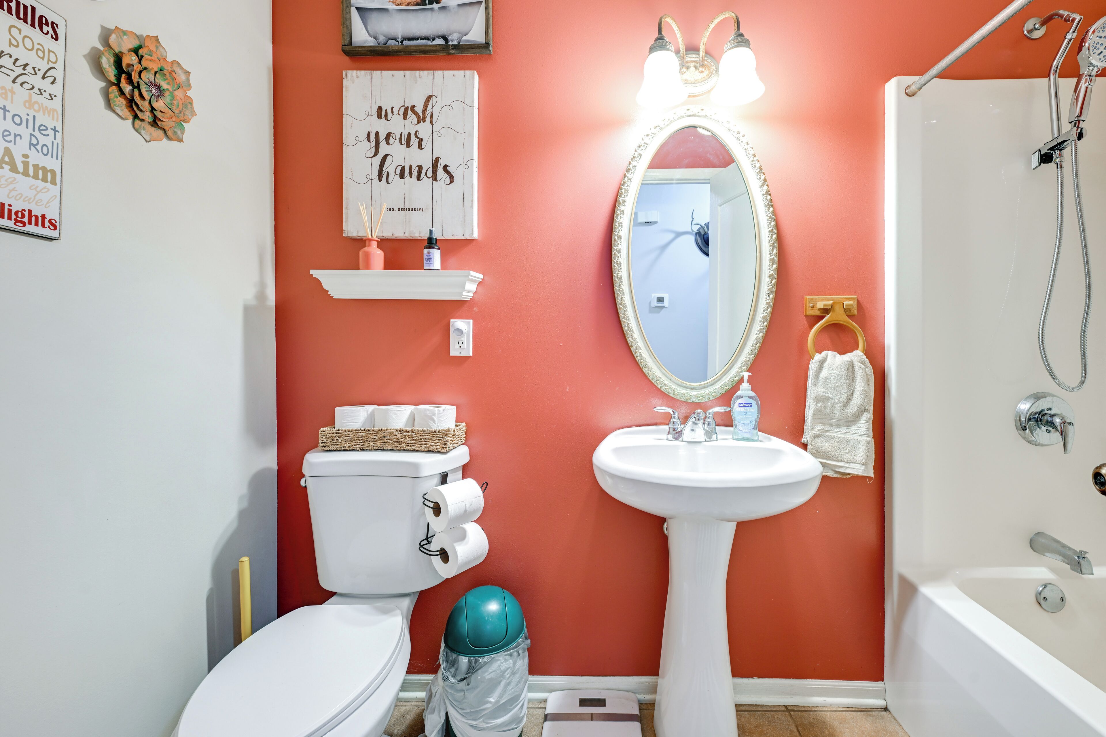A bathroom with a toilet, sink, and shower. There are toilet paper rolls, a soap dispenser, and a towel rack.