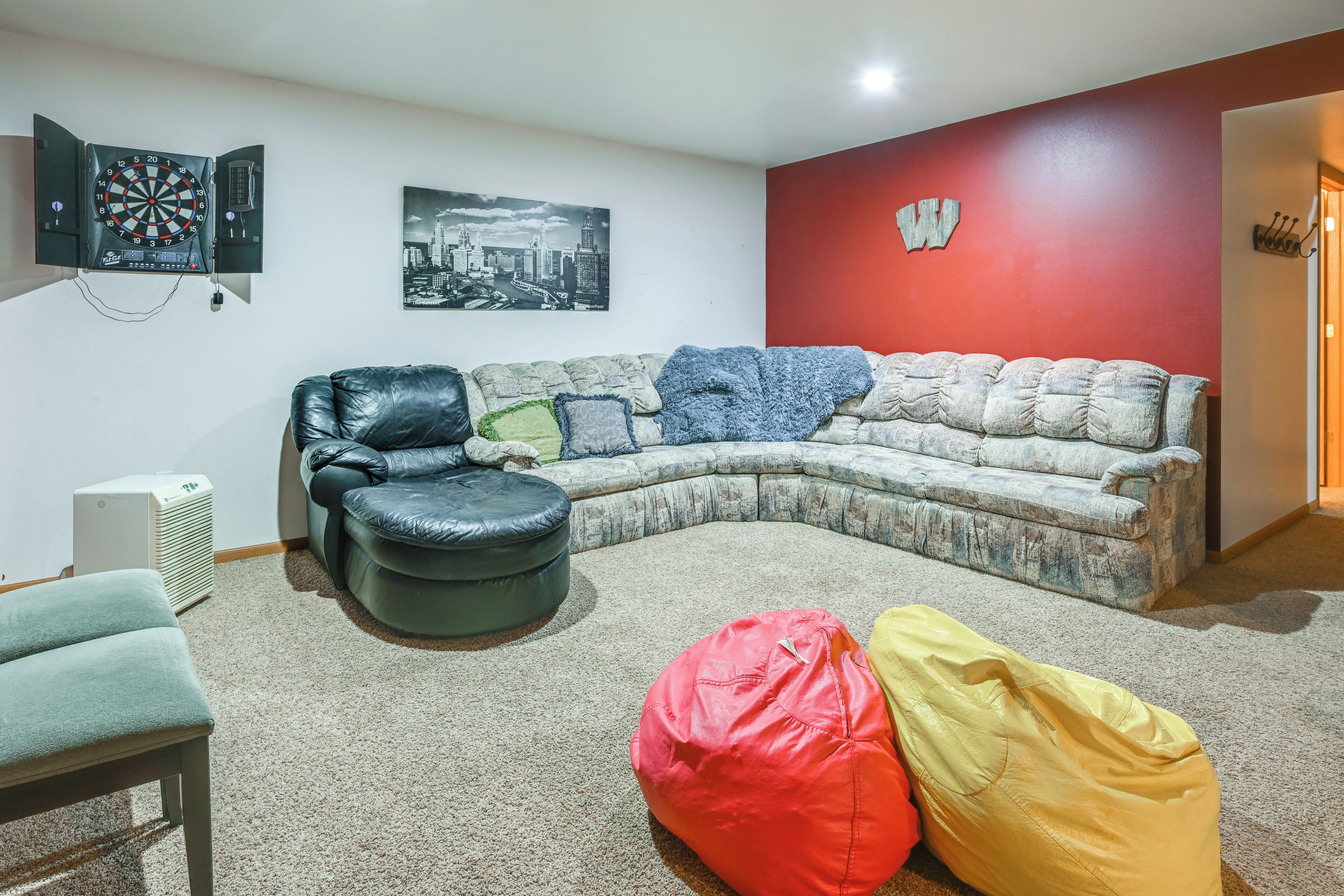 Una sala de estar con un sofá modular, un taburete de cuero negro y dos pufs.