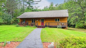 Une cabane en bois dotée d’une véranda, d’une porte d’entrée et d’un chemin menant à l’entrée.