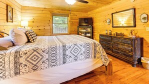 A wooden cabin bedroom with a bed, dresser, ceiling fan, and a window. - Deck & Mtn Views: 'sunset Ridge Cabin' in Murphy (Murphy)