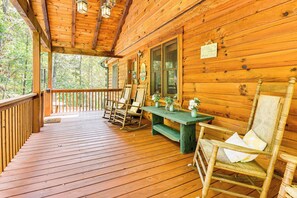 A wooden porch with rocking chairs and a table, surrounded by a wooden deck. - Deck & Mtn Views: 'sunset Ridge Cabin' in Murphy (Murphy)