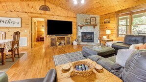 A cozy log cabin interior with a fireplace, a television, a dining area, and a comfortable seating area. - Deck & Mtn Views: 'sunset Ridge Cabin' in Murphy (Murphy)
