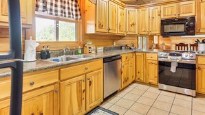 A kitchen with wooden cabinets, a stainless steel dishwasher, a microwave, and an oven. - Deck & Mtn Views: 'sunset Ridge Cabin' in Murphy (Murphy)