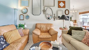 A living room with a brown leather sofa, a matching armchair, and a beige sofa with leopard print pillows. There are various framed mirrors and a chandelier on the wall. - Pool Access: Condo 4 Mi to Bradenton Riverwalk! (Bradenton)