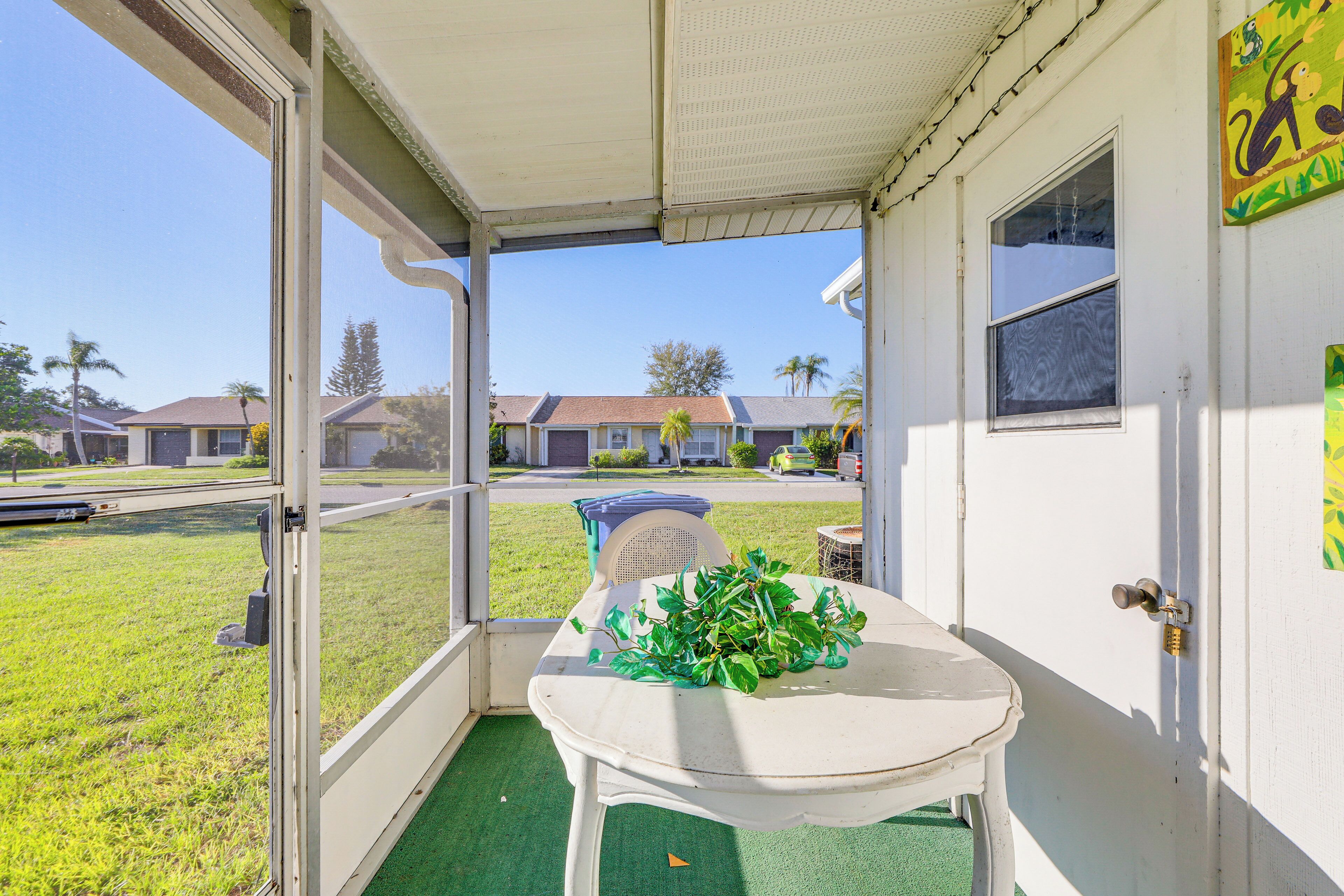 A room with a table and chairs, a view of houses outside, and a door with a lock.